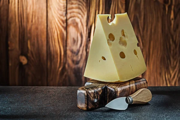 Big piece of milk maasdam cheese with knife on little vintage wo — Stock Photo, Image