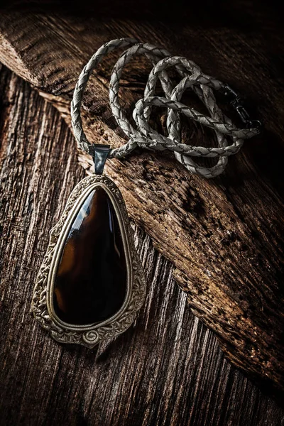 Кулон с темным камнем на винтажном дереве — стоковое фото