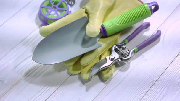 园艺工具黄色皮革工作手套手工铲子切割机和园艺绳在复古的白色粉刷木板上旋转 — 图库视频影像