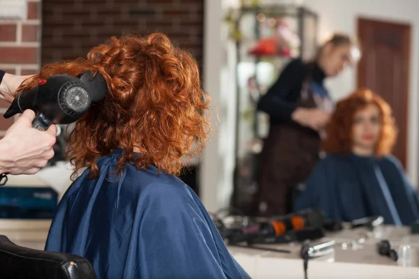 新しいヘアスタイルを美容師の女性になります ぼやけている鏡に映る ストック画像