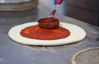 Pişirme pizza, aşçı koyar domates sosu