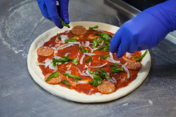 Cooking pizza in a restaurant, cook puts pizza ingredients