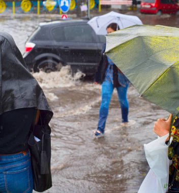 Women crossing flooded urban road in the heavy rain clipart