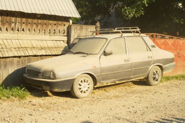 Car covered by dust on aa village street. Romania clipart