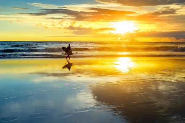 冲浪者的剪影走在沙滩上 并举行冲浪板与日落天际线在海浪 巴厘岛 印度尼西亚 — 图库照片