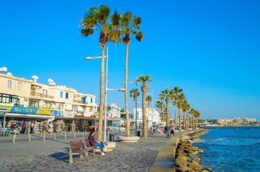 PAPHOS, CYPRUS - FEBRUARY 13, 2019: People on Paphos promenade at sunset. Paphos is the famous tourist destination in Cyprus clipart