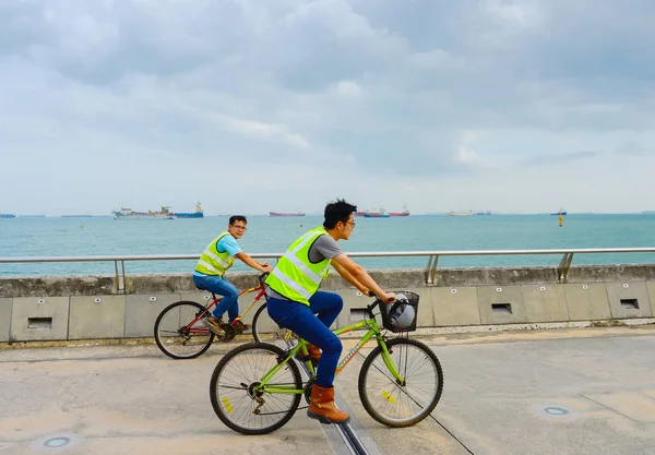 Worker bicycles Singapore harbor ships — Stock Photo, Image