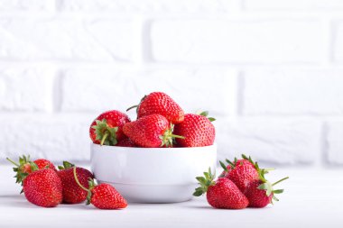 Yığın beyaz zemin üzerine seramik kase taze çilek