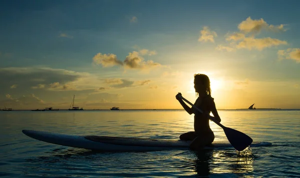 Happy woman on the SUP-board during sunset