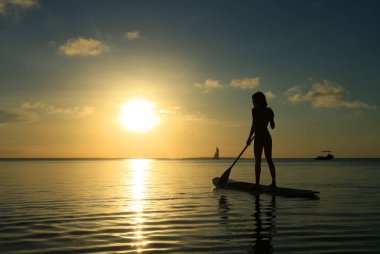 Gün batımı sırasında Sup tahta üzerinde mutlu kadın 
