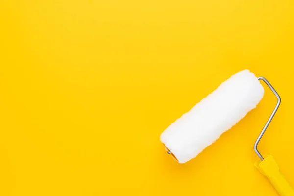 Paint roller on yellow background — Stock Photo, Image
