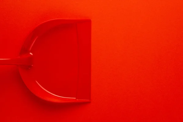Пластиковый совок на красном фоне — стоковое фото