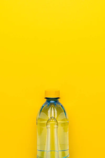 Botella de agua de plástico con tapa amarilla sobre fondo amarillo con espacio de copia —  Fotos de Stock