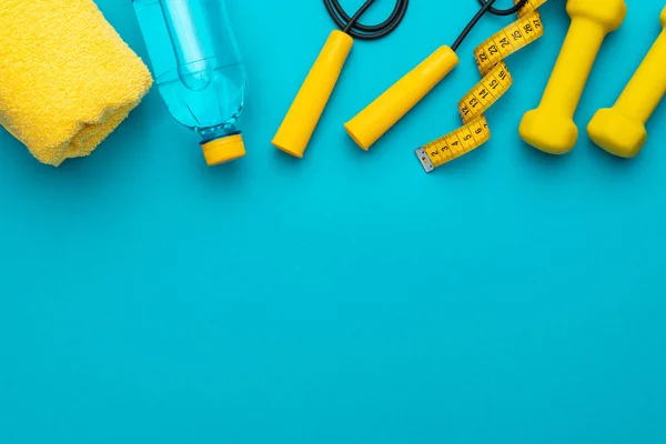 Flat lay photo of yellow fitness equipment in oder over turquoise blue backgound — Stock Photo, Image