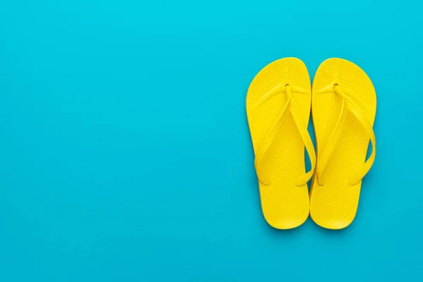 Pantai kuning flip-flops pada latar belakang biru — Stok Foto