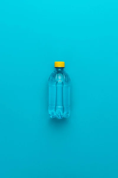 Mavi arka planda sarı kap ile plastik su şişesi — Stok fotoğraf