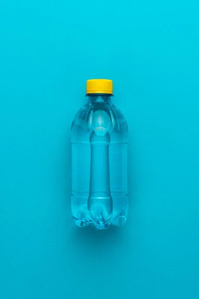 Bouteille d'eau en plastique avec bouchon jaune sur le fond bleu — Photo