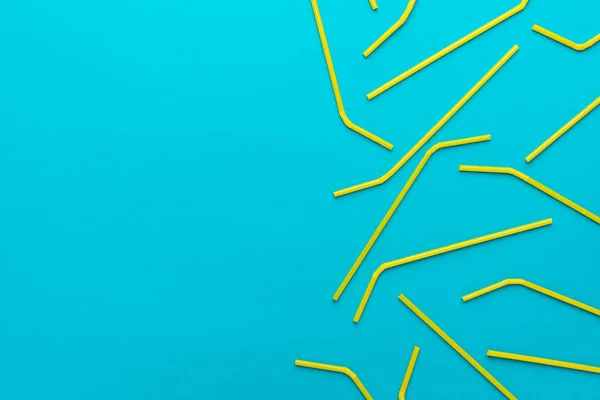 top view of cocktail straws on turquoise blue background with copy space