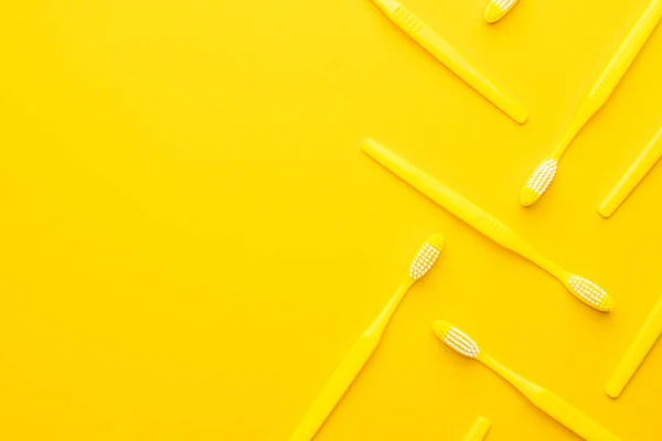 Plastikowe szczoteczki do zębów na żółtym tle — Zdjęcie stockowe