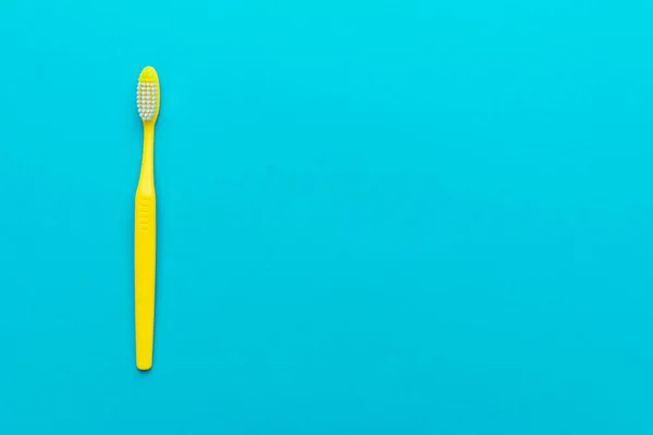 minimalist flat lay photo of yellow toothbrush over turquoise blue background