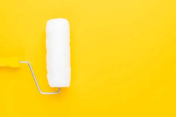 Clean paint roller with yellow handle on the yellow background with copy space — Stock Photo, Image