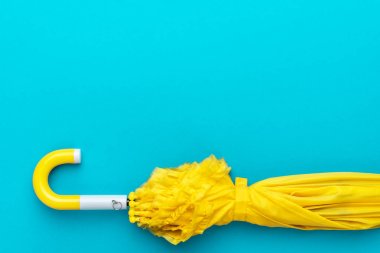 Turkuaz mavi arka planda katlanmış sarı şemsiye