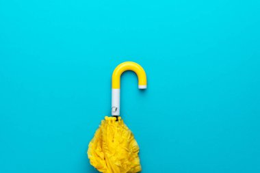 Turkuaz mavi arka planda katlanmış sarı şemsiye