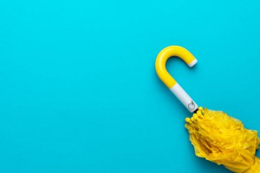 Turkuaz mavi arka planda katlanmış sarı şemsiye