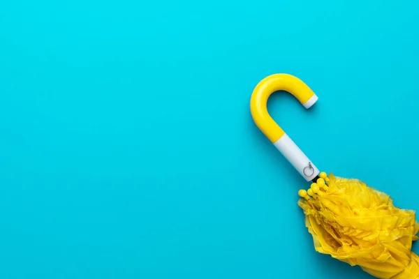 Folded yellow umbrella on turquoise blue background — Stock Photo, Image