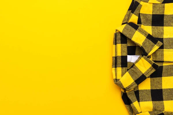 yellow and black checkered shirt on the yellow background with copy space