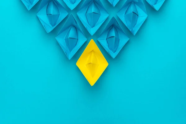 青の上に青いもののリーダーシップの概念の前に黄色の紙船のトップビュー — ストック写真
