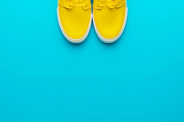 Flat lay foto de zapatillas amarillas sobre fondo azul turquesa con espacio para copiar —  Fotos de Stock