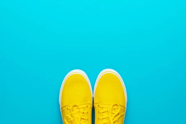 Paar gelbe Turnschuhe auf türkisblauem Hintergrund mit Kopierraum — Stockfoto