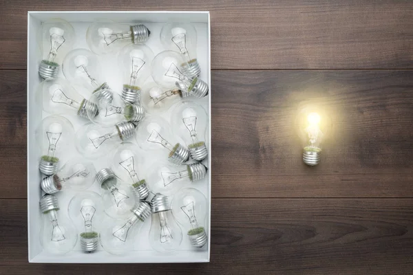 Lightbulb glowing outside the box as thinking out of the box concept — Stock Photo, Image