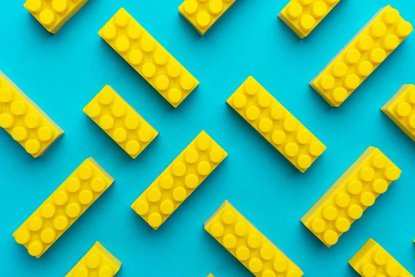 ターコイズブルーの背景を黄色のプラスチック製のビルディングブロック — ストック写真