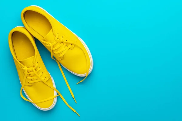 Vista superior de las zapatillas amarillas desatadas sobre fondo azul turquesa con espacio para copiar — Foto de Stock