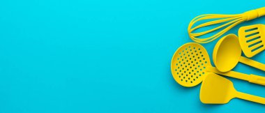 Kopyalama alanı ile turkuaz mavisi arka plan üzerinde sarı plastik mutfak gereçleri