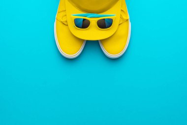 Sarı başlık, güneş gözlüğü, spor ayakkabısı turkuaz mavi arka plan ve fotokopi alanı