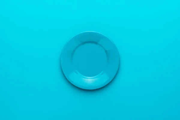 Bovenaanzicht van lege ronde blauwe plaat op turquoise blauwe achtergrond met Kopieer ruimte — Stockfoto