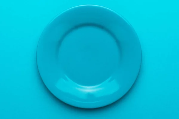Close up of empty round blue plate on turquoise blue background with copy space — Stock Photo, Image