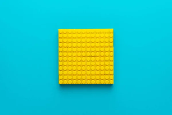 Foto plana minimalista de blocos de plástico amarelo com espaço de cópia — Fotografia de Stock
