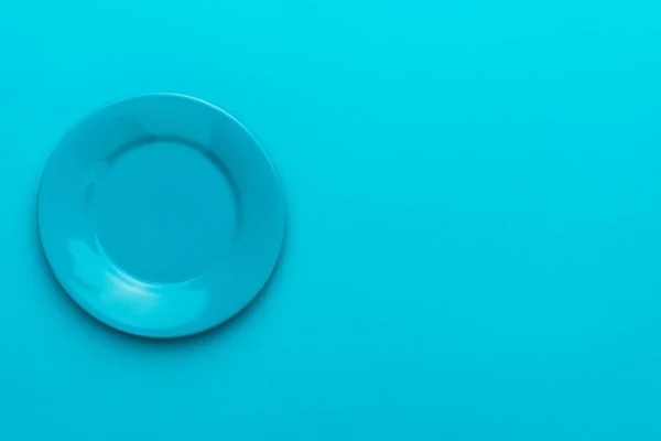 Вид сверху пустой круглой голубой тарелки на бирюзовом голубом фоне с пространством для копирования — стоковое фото