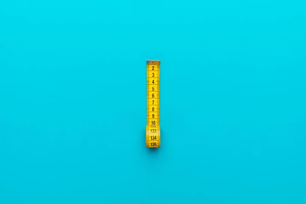 Nastro di misurazione giallo su fondo blu turchese con composizione centrale — Foto Stock
