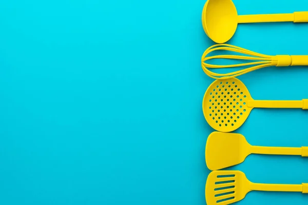 Louche jaune, fouet, écumoire, spatules sur table bleue turquoise avec espace de copie — Photo