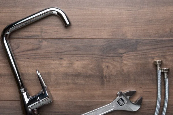 Grifo, llave inglesa, conectores flexibles de la manguera sobre fondo de madera con espacio de copia — Foto de Stock