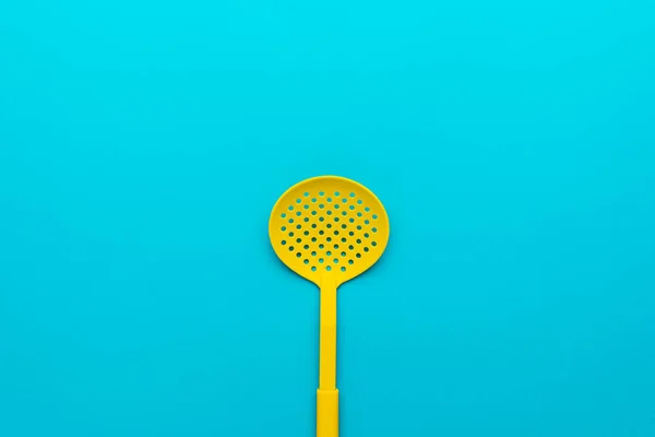 Top view of yellow skimmer spatula on turquoise blue background with copy space — Stock Photo, Image