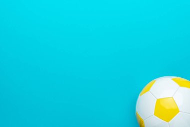 Turkuaz mavi arkaplanda fotokopi alanı ile futbol topunun minimalist fotoğrafı