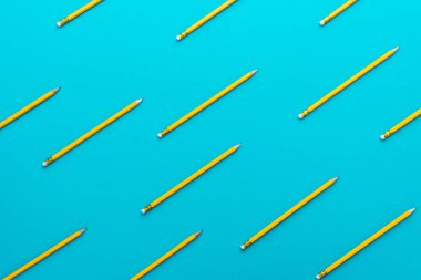 Turkuaz mavisi arka plan üzerinde keskinleştirilmiş basit sarı kalemlerüstte görünümü