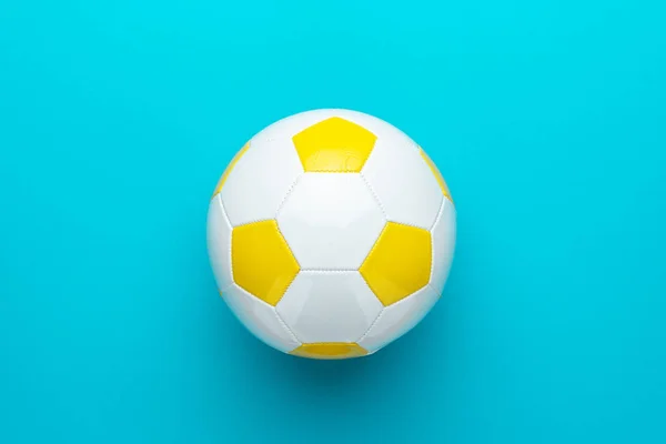 Primo piano del pallone da calcio bianco e giallo al centro dello sfondo blu turchese — Foto Stock