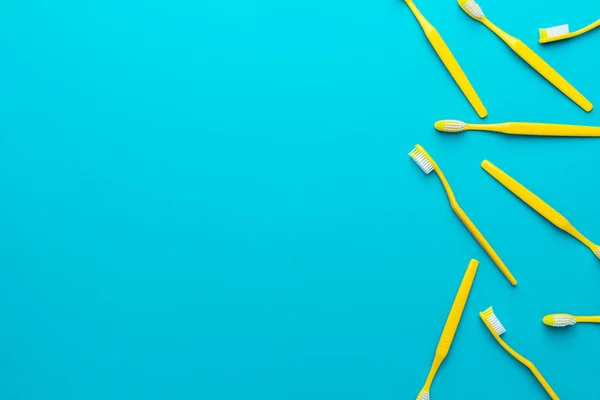 Top view of yellow toothbrushes over turquoise blue background with copy space — Stock Photo, Image